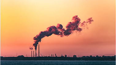 Industrial emissions with orange smoke against sunset
